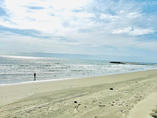 a person standing on a beach near the ocean at Kamizawa Villa - BBQ x オーシャンビュー in Kumiage
