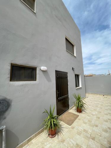 a white building with a door and two plants at Stay in the heart of Madaba in Madaba