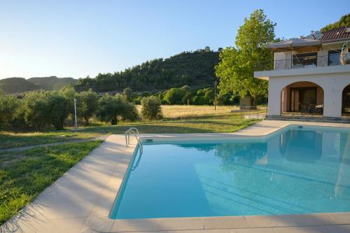 a swimming pool in front of a house at Antinea Olympian Villa in Olympia