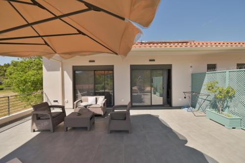 a patio with a couch and chairs and an umbrella at Antinea Olympian Villa in Olympia