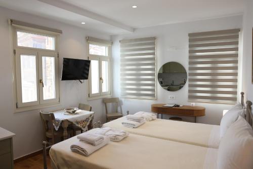 1 dormitorio con 2 camas, mesa y ventanas en Lythri Studios en Chios