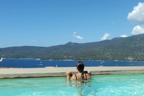 une femme en maillot de bain assise dans une piscine dans l'établissement Casa di l'Alivi - Villa avec vue exceptionnelle, à Propriano