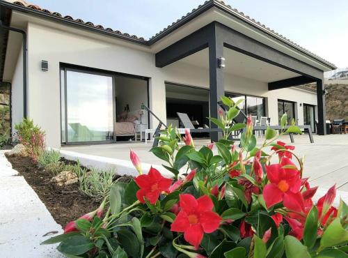 une maison avec des fleurs rouges devant elle dans l'établissement Casa di l'Alivi - Villa avec vue exceptionnelle, à Propriano