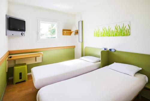 a room with two beds and a tv at ibis budget Chartres in Chartres