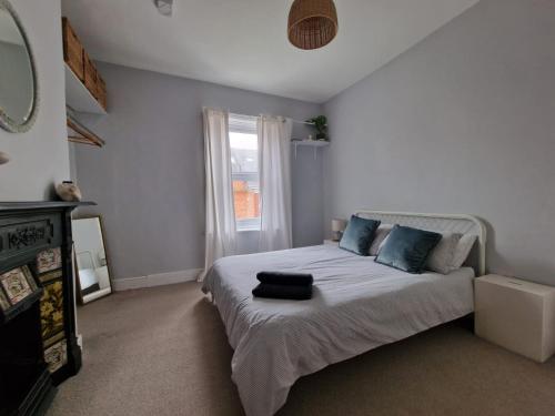 sypialnia z łóżkiem z niebieskimi poduszkami i oknem w obiekcie Lovely 3 bedroom Whitley Bay Townhouse. w mieście Whitley Bay