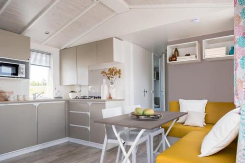 una cucina e una sala da pranzo con tavolo e divano di camping Le moulin a Patornay