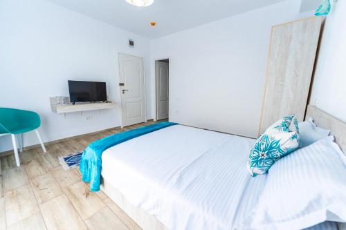 a white bedroom with a bed and a tv at Babilon in Sarichioi