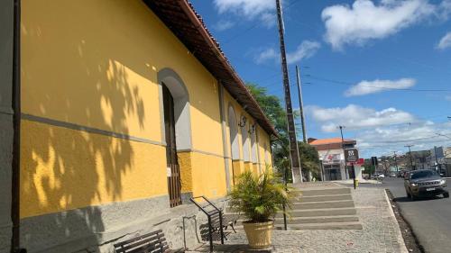 a yellow building with a plant on the side of it at Casa Feliz em Gravatá - A 100 metros do Pátio de Eventos in Gravatá