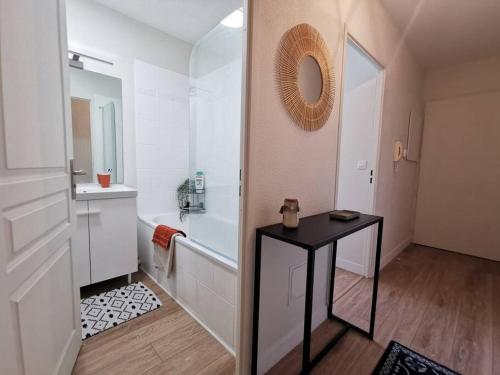 La salle de bains est pourvue d'une baignoire, d'une table et d'un miroir. dans l'établissement Agréable T2 lumineux 4 couchages tout équipé, à Ludon-Médoc