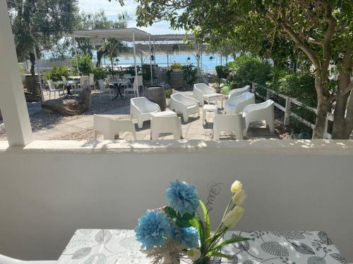 un gruppo di sedie bianche e un tavolo con fiori blu di Appartamenti sul mare da Antonino a Mattinata