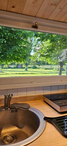 a kitchen sink with a large window above it at Les Cocons d AleXan Le Chalet balnéo aromathérapie in Quinssaines