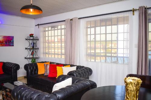 a living room with black leather couches and a table at House of Grace Nakuru Naka Area Airbnb in Nakuru