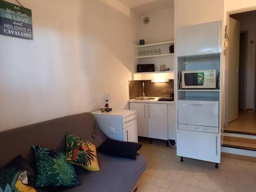 un salon avec un canapé et une cuisine dans l'établissement Location dans résidence calme, proche mer, à Cavalaire-sur-Mer