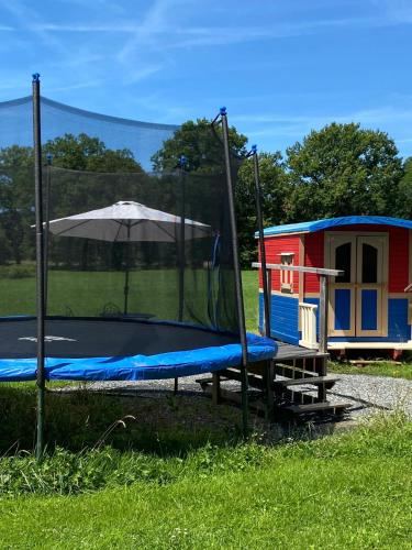 a playground with an umbrella next to a house at Bungalow charmant à Saint-Pardoux avec piscine partagée in Saint-Pardoux
