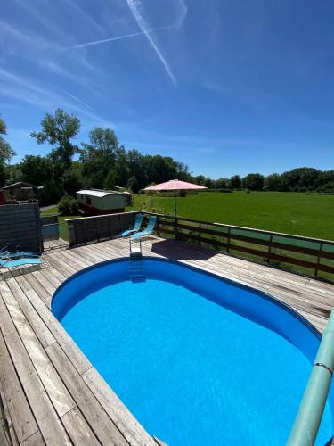 une grande piscine bleue sur une terrasse en bois dans l'établissement Bungalow confortable à Saint-Pardoux avec piscine partagée, à Saint-Pardoux