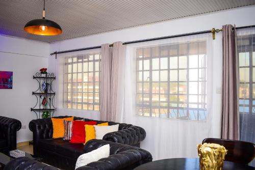 a living room with a black leather couch with colorful pillows at House of Grace Nakuru Naka Area Airbnb in Nakuru