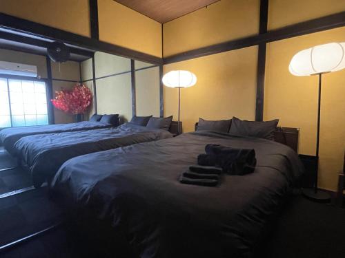 TRAVELERZ YOKOHAMA Demon Slayer House في Kikuna: سريرين في غرفة بها مصباحين ومناشف