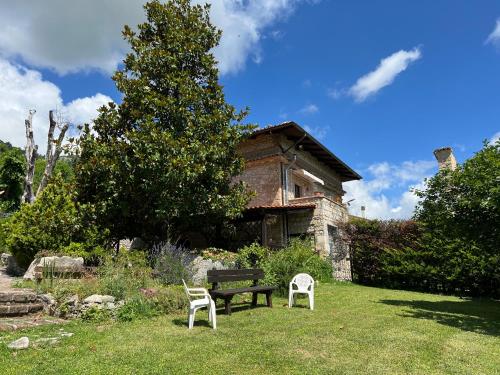 a bench and two chairs in front of a house at B&b La Baronata - Pescosansonesco (Pe) in Pescosansonesco
