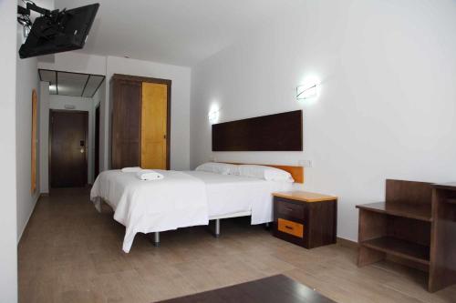 a bedroom with a large white bed and a table at Hotel Lorenzo in El Contador
