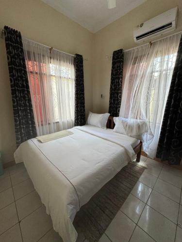 ein großes Bett in einem Schlafzimmer mit zwei Fenstern in der Unterkunft G & S Executive Lodge in Daressalam