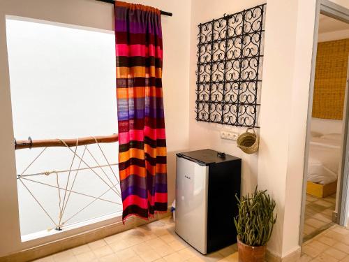 a small refrigerator in a room with a window at Taouarguit Guest House in Imsouane