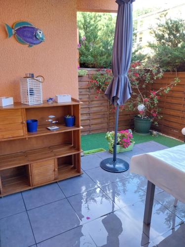 un parasol dans un patio avec une table et un poisson sur le mur dans l'établissement T1 Lavandou La favière en rez de jardin bord de mer, à Bormes-les-Mimosas