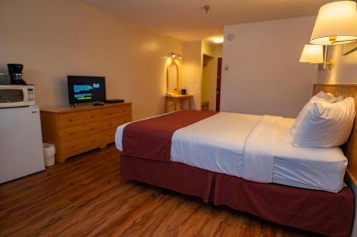 a hotel room with a bed and a television at Canadas Best Value Inn- Riverview Hotel in Whitehorse
