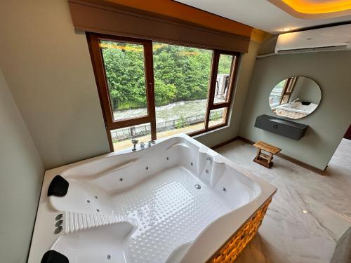 bañera blanca grande en el baño con ventana en TUVA VİLLA Bungalov en Çamlıhemşin