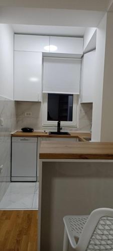 a kitchen with white cabinets and a desk with a television at Luxury Apartment IVA III in Skopje