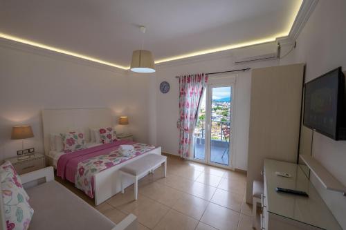 a white bedroom with a bed and a balcony at Hotel Mira Mare in Ksamil