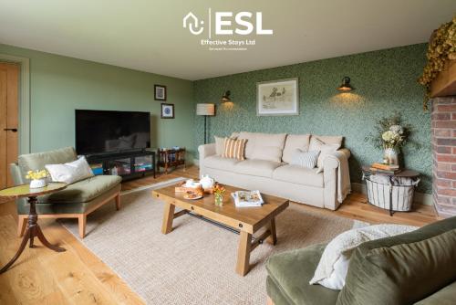 a living room with a couch and a table at Large Country Farmhouse with Hot Tub and Shropshire Hills View in Minsterley