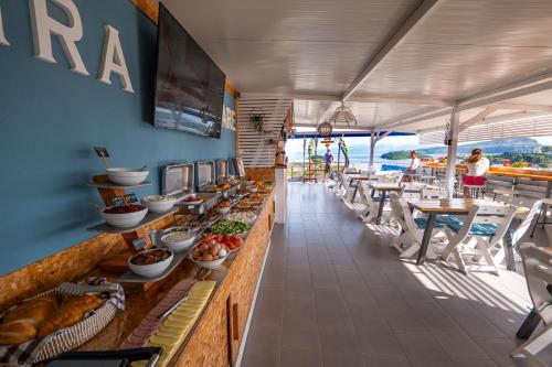 a buffet line in a restaurant with tables and chairs at Hotel Mira Mare in Ksamil