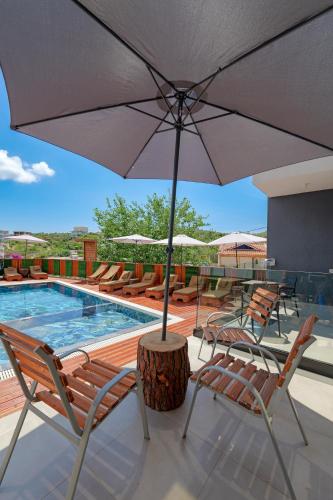 a patio with chairs and an umbrella next to a pool at Hotel Mira Mare in Ksamil