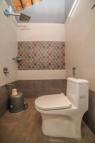 a bathroom with a white toilet in a room at Rain Rock Villa in Yercaud