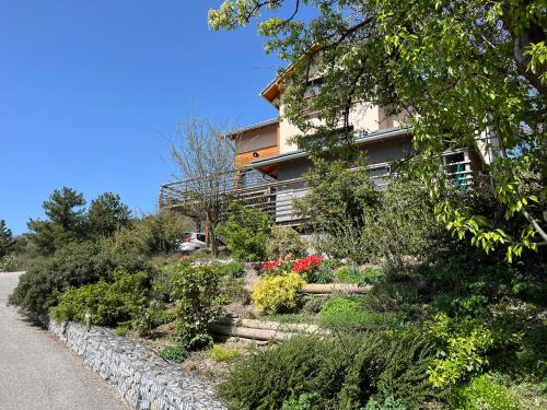 a house on the side of a hill with flowers at Gîte la biche des écrins in Prunières