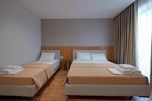 two beds in a hotel room with a window at Hotel Ajden by Mira Mare in Ksamil