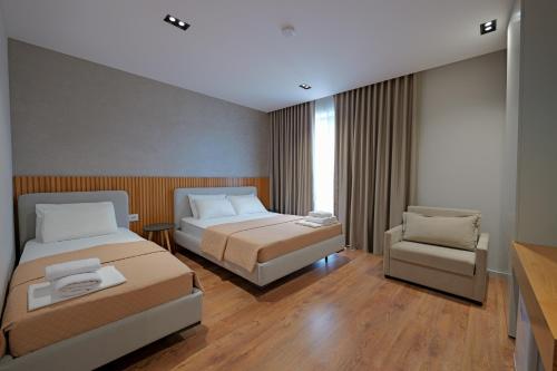 a hotel room with two beds and a chair at Hotel Ajden by Mira Mare in Ksamil