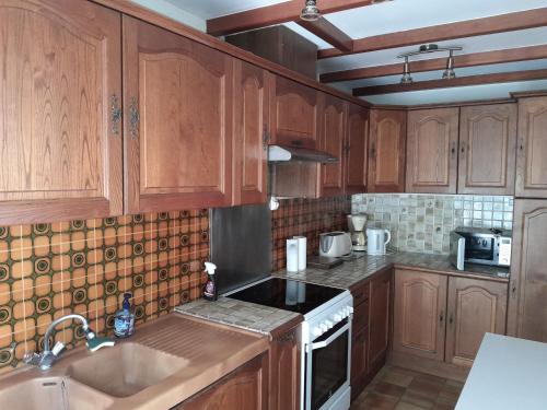 une cuisine avec des armoires en bois, un évier et une cuisinière dans l'établissement Gîte au cœur des châteaux de la loire, à Lignières-de-Touraine