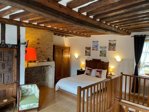 ein Schlafzimmer mit einem Bett und einem Kamin in der Unterkunft Le Douet Fleury - Gîte de Jardin in Livarot