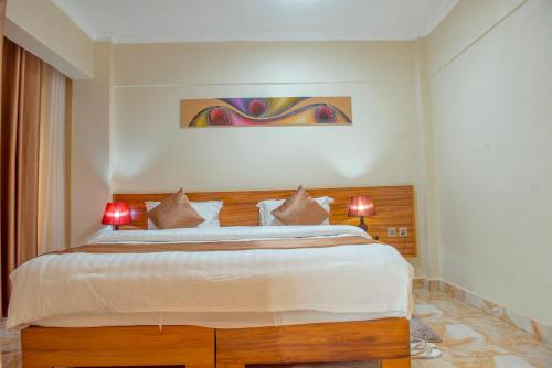 a bedroom with a large bed with two red lamps at Mountain View Hotel & Apartment in Kigali