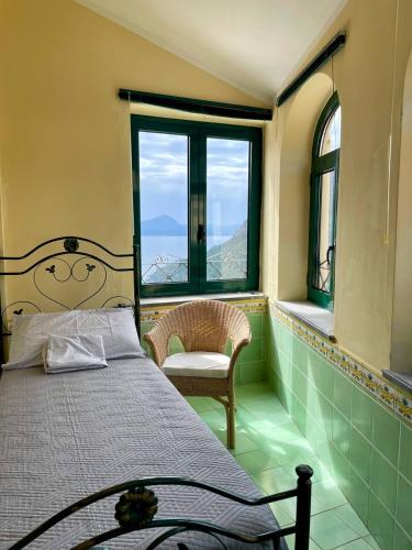 a bedroom with a bed and a window and a chair at Smeraldo Holiday in Maratea