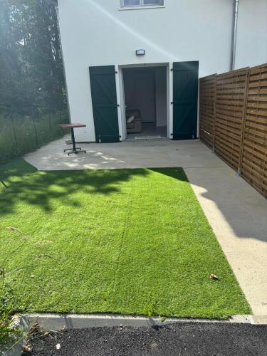 une cour avec de l'herbe verte devant un bâtiment dans l'établissement Magnifique T2 neuf au centre de Cambo les bains, à Cambo-les-Bains