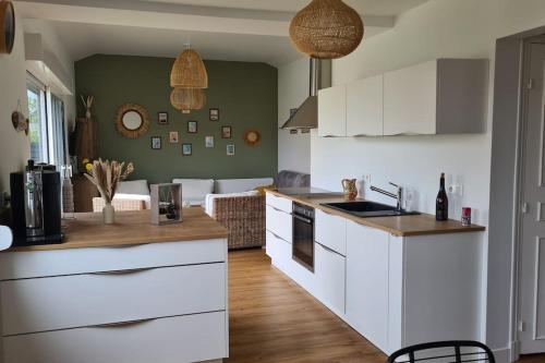 une cuisine avec des armoires blanches et un salon dans l'établissement Villa rénovée 350 m de la mer, à Hauteville-sur-Mer