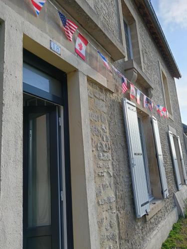 a building with american flags on the side of it at CAP MANVIEUX Gîtes in Manvieux