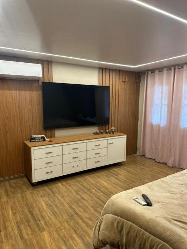 a bedroom with a flat screen tv on a dresser at Casa pertinho da praia com hidro in Rio das Ostras