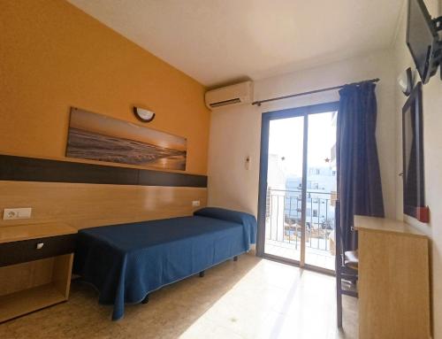 a bedroom with a bed and a sliding glass door at Hostal Horizonte in San Antonio