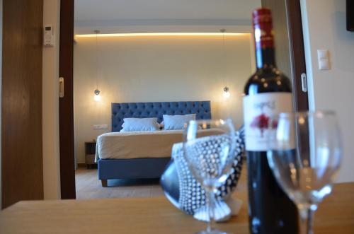 Odysseus Hotel في باليوكاستريتسا: غرفة نوم مع سرير وزجاجة من النبيذ على طاولة