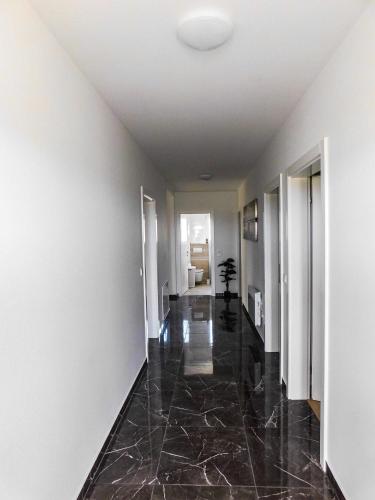 a hallway with a black marble floor and white walls at Vila Baruni in Sukošan