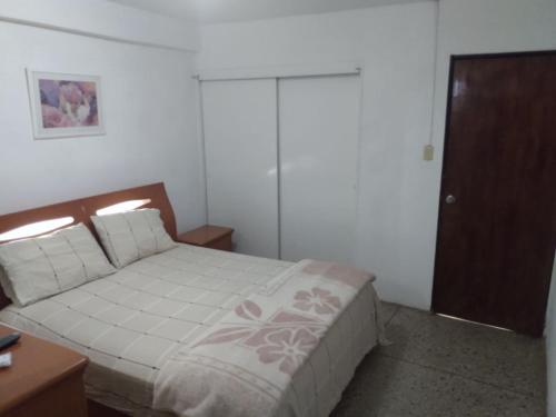 1 dormitorio con 1 cama y armario de madera en Habitación para una persona en Puerto La Cruz
