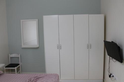 a bedroom with white cabinets and a bed and a mirror at Blue Apartments & Hotel Shengjin in Shëngjin